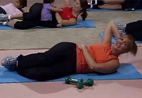 A woman is lying on the floor doing crunches.