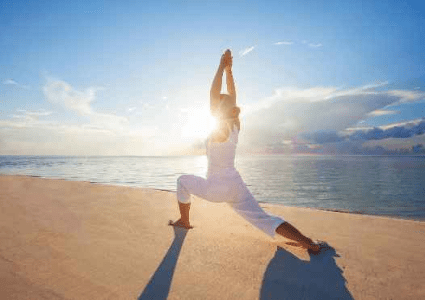 A woman is doing yoga on the beach